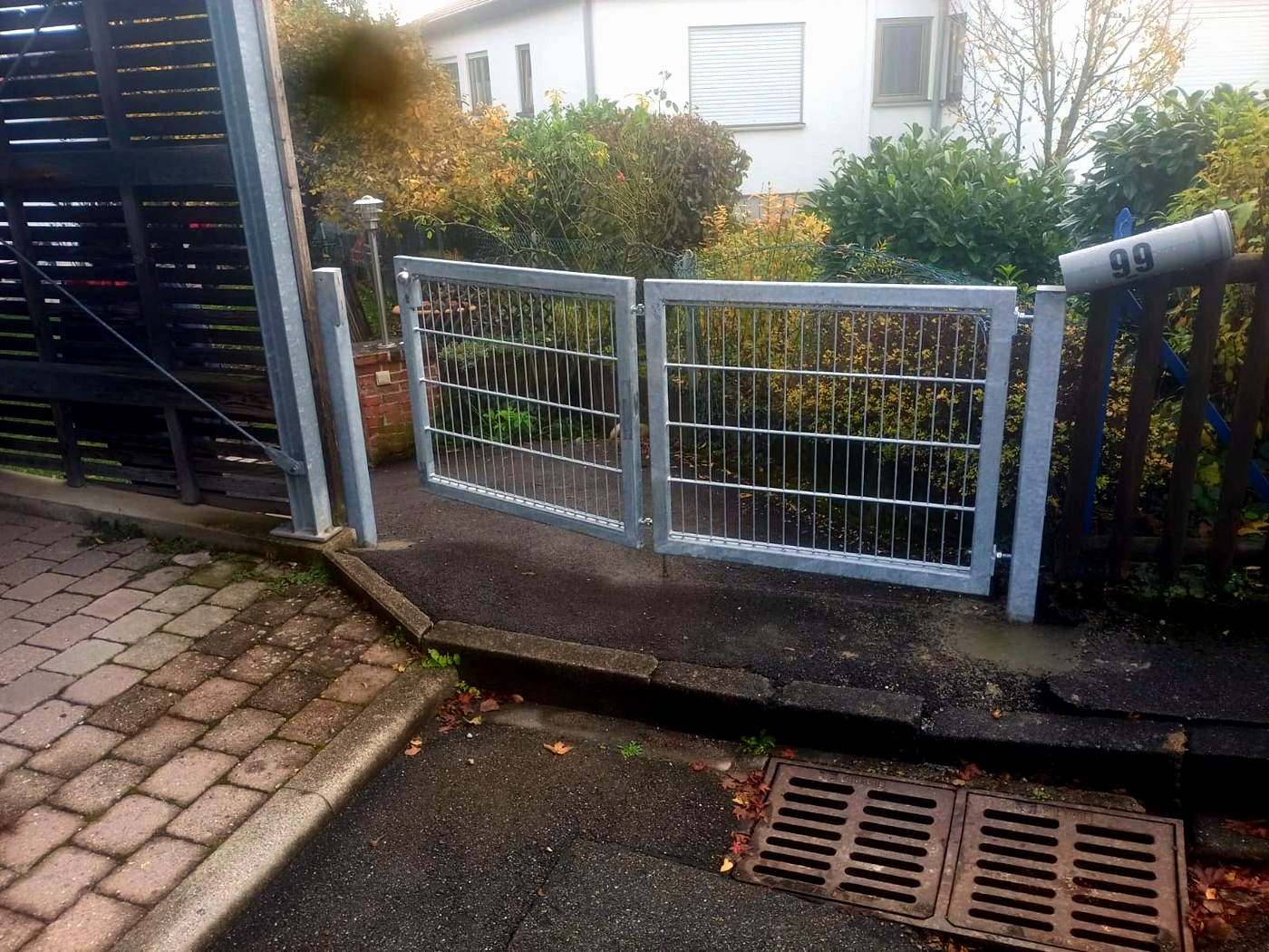 Helles zweiflügeliges Gartentor mit Gitterfüllung neben einer Außentreppe.